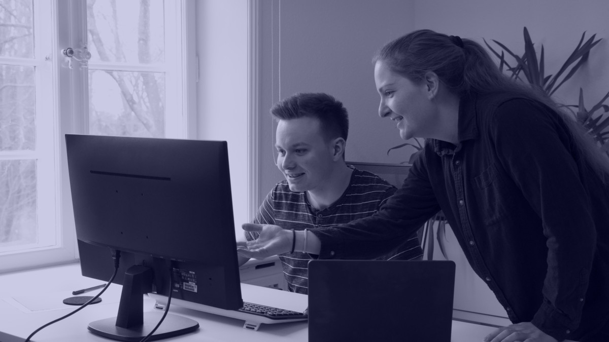 Zwei Personen diskutieren etwas vor einem Monitor.